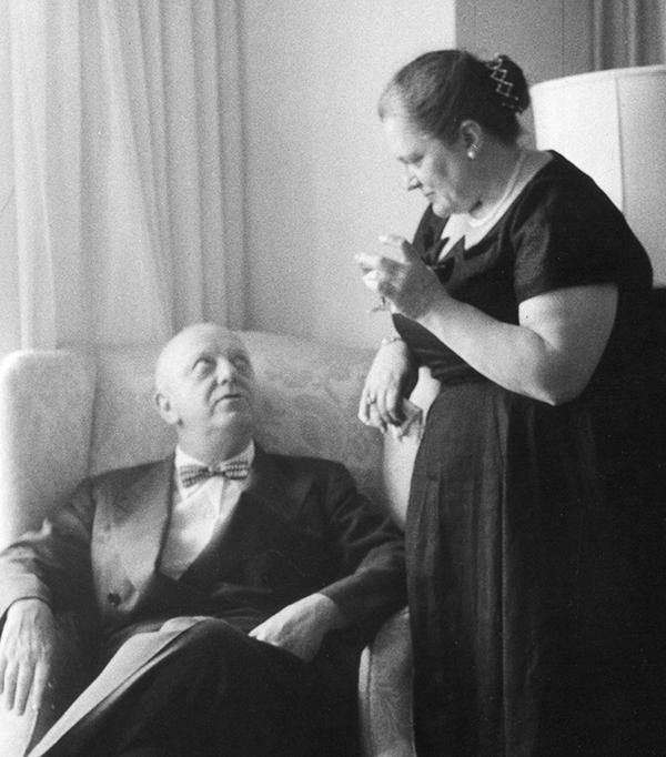 black and white photo of woman standing spekaing with bald man seated